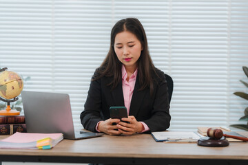 Asian Woman Lawyer Using Smartphone at Desk