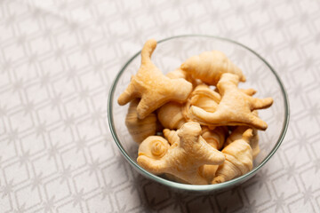 Mini croissants and cat shaped cookies in glass bowl on patterned tablecloth, top view