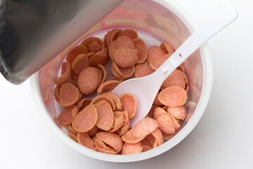 A bowl of pinky colored crispy corn flake cereal isolated on white background.