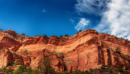 Fototapeta premium Steep Red Rock Cliff Background Under Blue Cloudy Sky