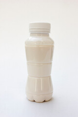 A white plastic bottle containing milk on a white background.
