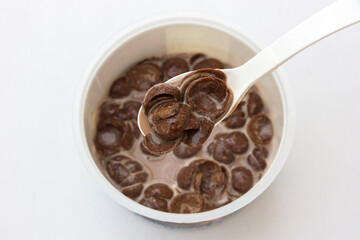 A bowl of chocolate cereal with chocolate milk on a white background. Delicious nutritious Breakfast for the child