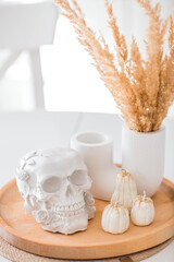 Halloween celebration. A white skull and pumpkins on the table. Decor for the Day of the Dead or Halloween in the kitchen interior.