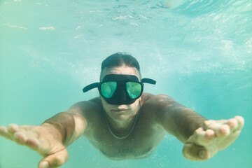 Naklejka premium Man enjoys swimming underwater in clear blue water wearing a mask and fins during sunny daytime activity
