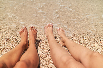 Friends enjoy sunny day at the beach, relaxing with toes in the water