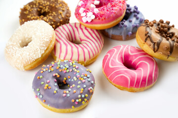 Colorful assortment of donuts with various toppings displayed on a white surface