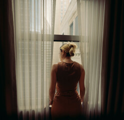young woman looking out window New York City 