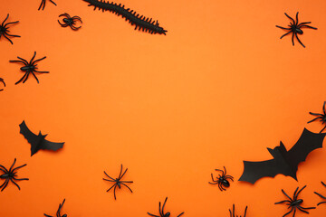 Halloween background with spiders as symbols of Halloween on orange background. Space for text