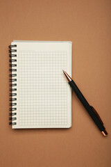 Notebook with black pen on brown background. Vertical photo
