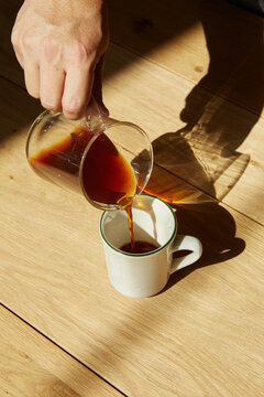Hand pouring pour over coffee into mug