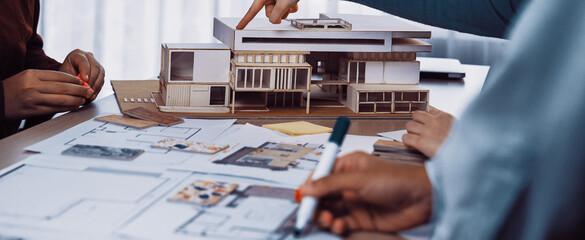 A collaborative design session featuring a scale model of a modern building, architectural blueprints, and engaged professionals brainstorming innovative ideas and solutions. SACTR