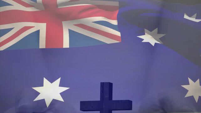 Memorial cross anchoring center while wind rippling flag revealing Union Jack and Southern Cross