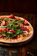 Pizza with salami, mozzarella cheese, black olives and pepper. Rustic wooden background. Soft focus. Copy space.	
