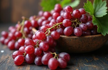 Close-up of fresh red grapes in a rustic bowl and on dark wood. Juicy berries with green leaves are ripe and ready for harvest. Healthy food, natural fruit, farm product.