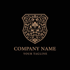 Ornate shield emblem with intricate floral scrollwork and elegant text for company branding.