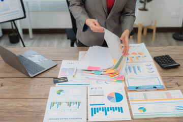 Businesswoman browsing through various documents, efficiently organizing files and managing paperwork in a bustling office environment, tackling deadlines and ensuring smooth operations
