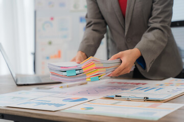 Businesswoman browsing through various documents, efficiently organizing files and managing paperwork in a bustling office environment, tackling deadlines and ensuring smooth operations