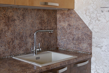 Interior of modern kitchen with sink and chrome faucet against stone wall, household lifestyle concept.