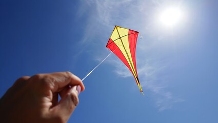 Flying a colorful kite against a vibrant blue sky backdrop outdoors