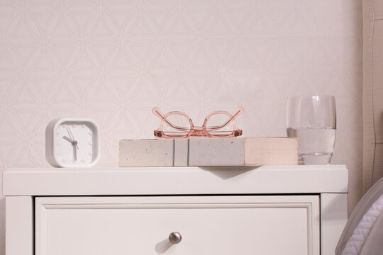 Bedroom still life with pink glasses, alarm clock, and book