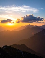 Obraz premium A breathtaking mountain vista bathed in the warm hues of a spectacular sunset.