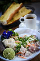 Close up of a poisson cru served with a cup of coffee and bread. 