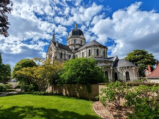 Cathedral with dome and spire behind trees and garden on sunny day