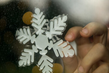 Close up of a child gluing snowflakes on the window