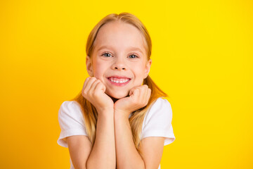 Smiling young girl in a white t-shirt on a vibrant yellow background exuding happiness and innocence