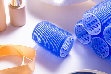 Set of Blue Plastic Hair Rollers with Hair Care Products on White Table