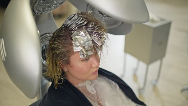 Accelerating the process of hair coloring with climazone. A woman sits under the machine in a hairdresser's salon.