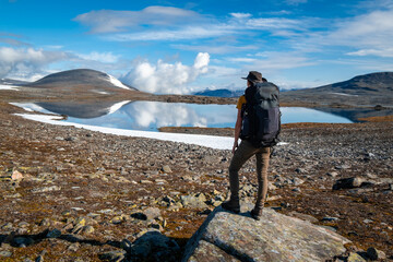 Woman with backpack near mountain lake in Sarek National Park, Sweden