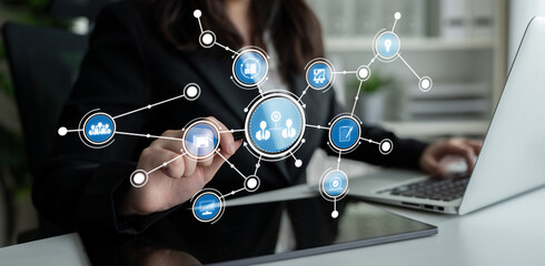 A professional woman engages with a digital interface showcasing networking and communication elements in a modern office setting, highlighting innovation and interaction. Crux