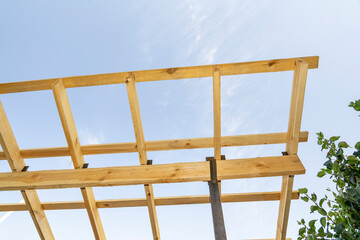 Wooden construction frame with beams against blue sky. Architectural detail and building structure concept.