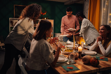 Friends serving food at thanksgiving dinner table