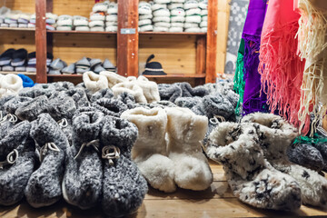 Handmade warm felt slippers for sale in a cozy winter market stall.