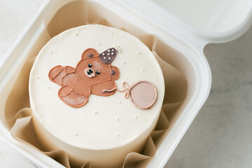 Little birthday bento cake in a gift box decorated with cute cream teddy bear with balloon. Birthday cake for a kid on the white marble background