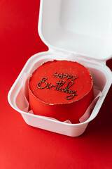 Little red birthday bento cake with funny congratulation text  on top in a white gift box. Red background