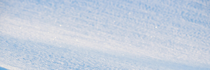 Obraz premium Beautiful winter background with snowy ground. Natural snow texture. Wind sculpted patterns on snow surface. Wide panoramic texture for background and design. Closeup top view with copy space.