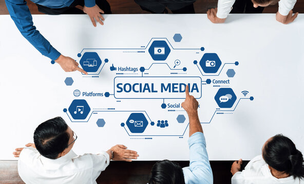 A diverse group of professionals collaborates around a table, analyzing social media strategies represented by various icons and elements of digital communication and marketing. Amity