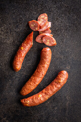 Sliced smoked ​​sausage on black table. Top view.