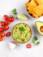Appetizer guacamole with corn chips nachos, ingredients on light background. Top view. Mexican food.