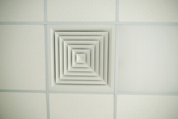Square ventilation grille integrated into suspended ceiling tiles ensures proper air circulation...