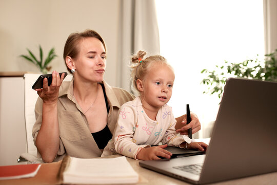 Mother multitasking with work while caring for her daughter at home