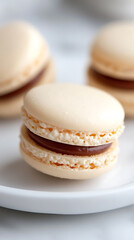 Delicious-looking cream colored macarons with rich chocolate filling. These French treats are perfect for any celebration or gathering of friends.