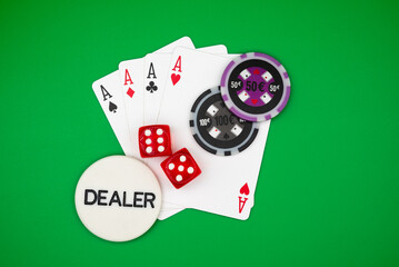 Four aces poker hand with colorful casino chips, dice and dealer button on green table – symbol of gambling, luck, risk, addiction and casino games.