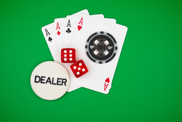 Four aces poker hand with black casino chips, dice and dealer button on green table – symbol of gambling, luck, risk, addiction and casino games.