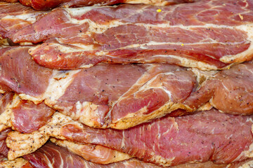 Raw pork meat slices marinated with spices and herbs stacked together, close-up texture background for cooking barbecue