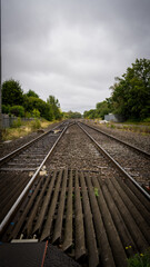 Fototapeta premium Railroad tracks converging into the distance under a cloudy sky
