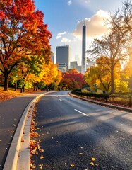 A picturesque autumnal road winds through a park, showcasing vibrant fall foliage and a modern cityscape.